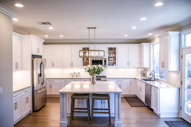 Interior of a modern kitchen with white cabinets and chrome appliances